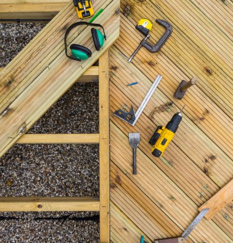 Deck tools and deck under construction Top down image of a desk under construction showing joists, planks and tools used