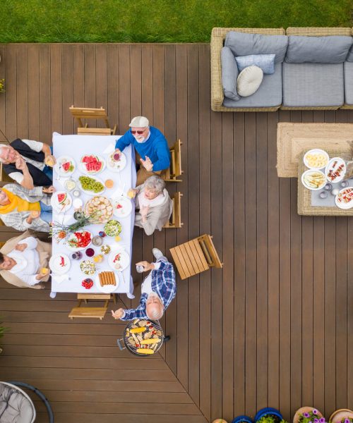 Sitting by the table Group of senior friends sitting by the table on a terrace in the backyard